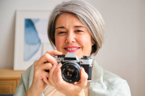 istock A mature woman is holding a camera and smiling 2155318729