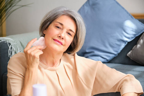 istock A mature woman is making her skincare routine using a rose quartz gua sha 2155319659