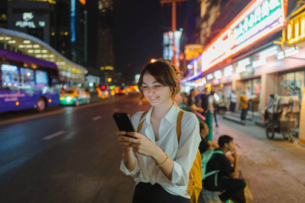 istock woman using smartphone walking in Bangkok city at night 2155321723