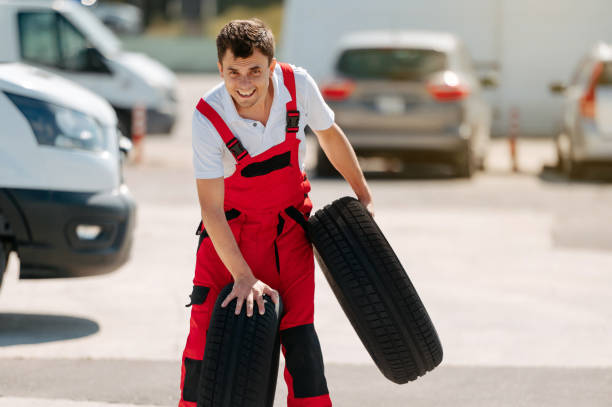 istock Young smiling man, in red coverall,  car mechanic holding auto tires 2155322017