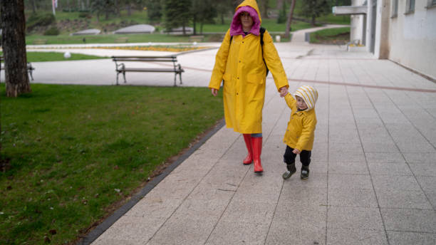 istock Mother and son in raincoats walking in rain 2155323183