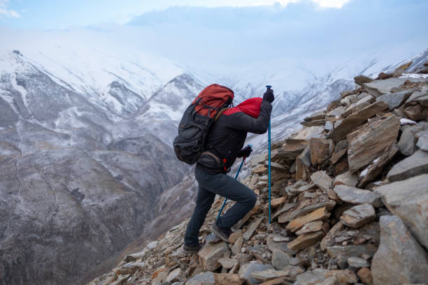 Successful man backpacker hiking in winter mountains