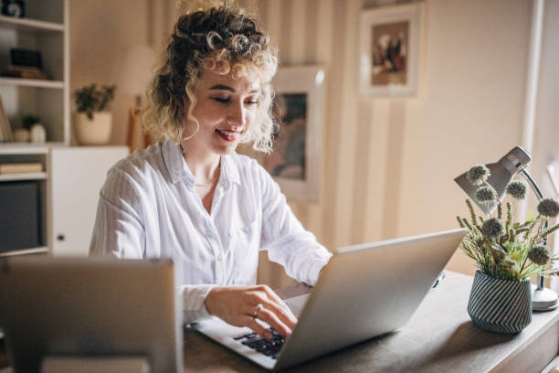 istock Woman typing happily at home desk 2155324739