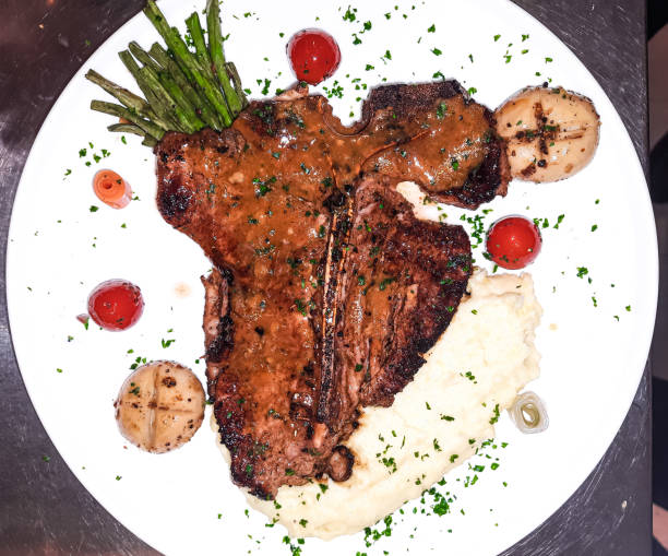 Grilled meat dinner plate. Cooked beef T-bone steak with vegetables and fresh vegetables. Tender grilled porterhouse or T-bone steak served with mashed potato and grilled mushroom. Grilled meat dinner plate. Cooked beef T-bone steak with vegetables and fresh vegetables. Tender grilled porterhouse or T-bone steak served with mashed potato and grilled mushroom. steakhouse stock pictures, royalty-free photos & images