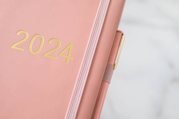 istock Pink coral colored diary for the year 2024, pen, marble background 2155327745