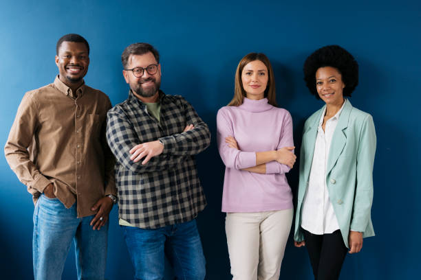 Multicultural group of people standing together and smiling against blue wall