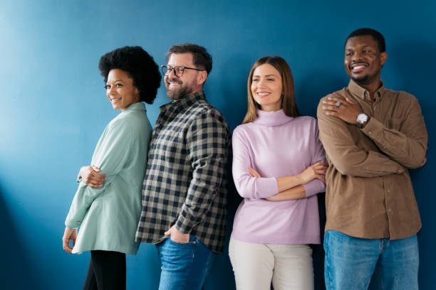 istock Diverse group of people standing together and smiling against blue wall 2155334571