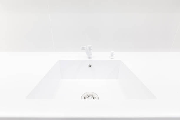 Modern trendy snow white kitchen interior with acrylic countertop, integrated acryl sink and monochrome faucet and  detergent pump dispenser, design, image with selective focus