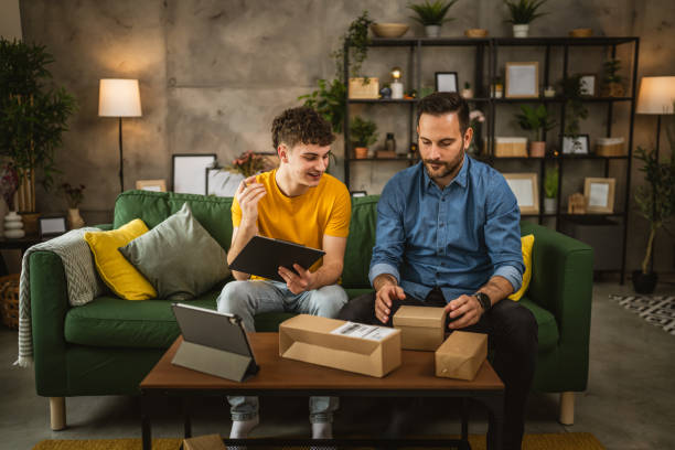 istock Two caucasian men pack and check package together at home 2155337576