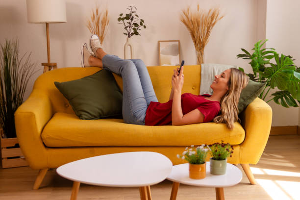 istock Woman relaxing on couch with smartphone 2155337888