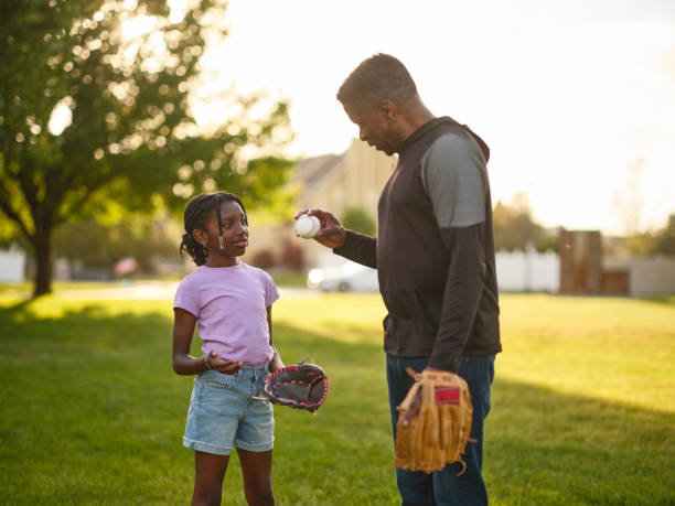 istock Grandfather and Granddaughter Practicing Baseball in a Park 2155340431