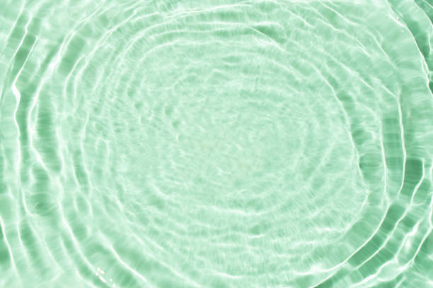 Flowing water with shining wave texture on a vibrant sunlight mint green background. Abstract Water surface background idea. Abstract summer template background.