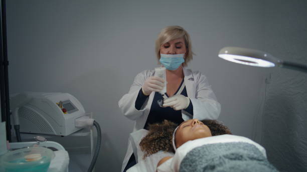 istock Cosmetician squeezing face mask into jar. African american visit dermatologist 2155343924