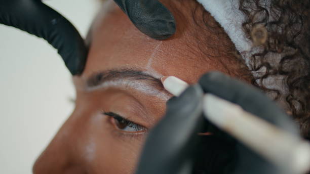 istock Closeup cosmetician marking brows with pencil. Hands in gloves shaping contour 2155348211