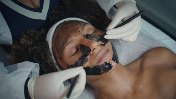 istock Hands applying face mask in spa salon closeup. Relaxed patient visit cosmetician 2155348823