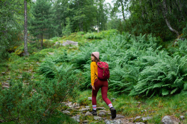 Woman hiking through dense forest in Norway