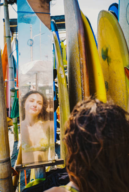 istock Woman looking at mirror near surfboards 2155349484