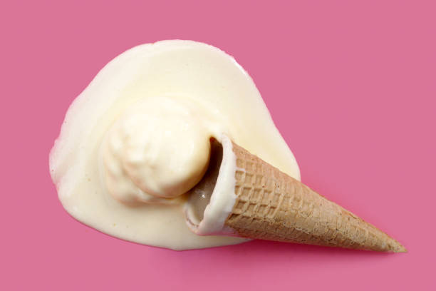 Melting ice cream ball with waffle cone on pink background.