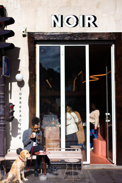 Paris, France: A woman sits with her dog relaxing outside the Noir cafe in the 9th arrondissement with a take-away coffee.