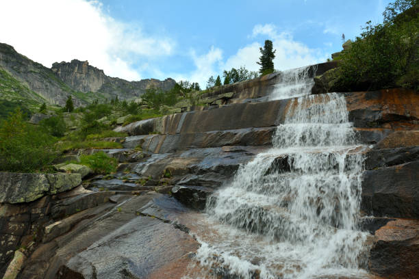 istock A high rock in the form of stone steps and a cascading mountain river form a waterfall on a cloudy summer day. 2155361513