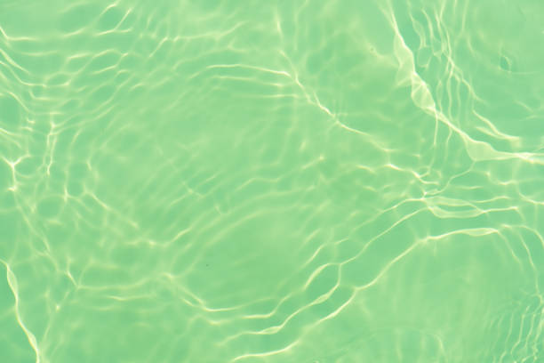 Blue water with ripples on the surface. Defocus blurred transparent blue colored clear calm water surface texture with splashes and bubbles. Water waves with shining pattern texture background.