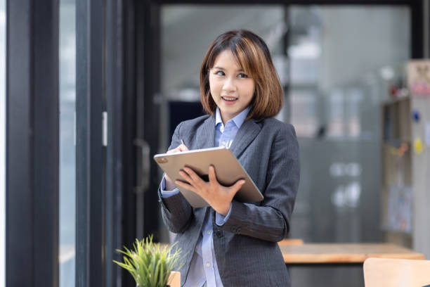 istock Attractive  Asian businesswoman using tablet and working at desk in office. 2155368334