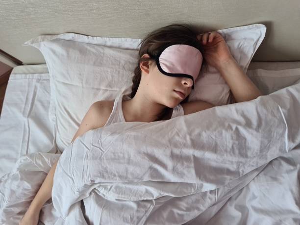 Young Girl Sleeping in Bed With Pink Sleep Mask