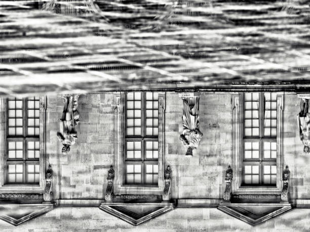 The City of Paris France on October 23, 2023:  Part of the facade of the  Louvre Museum reflected upside down in a fountain pond, in Paris France