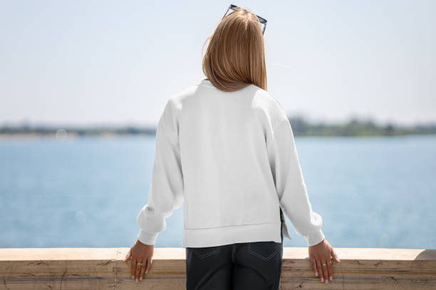 istock White sweatshirt template with side slits on girl, back view, lady on quay, blurred river background. 2155384733