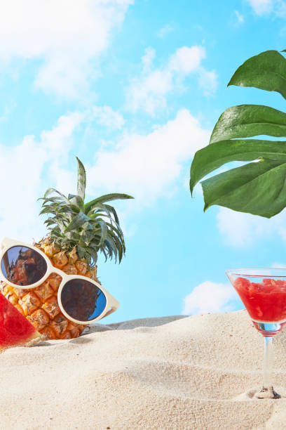 istock Yellow sand beach side against the background of blue sky and white clouds, a pineapple, watermelon and green monstera decorated both sides, leaving a blank space in center for displaying product 2155390953