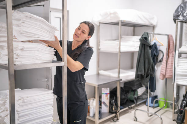 istock Mid adult maid packing bed sheets on shelf in hotel laundry 2155396978