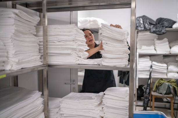istock Mid adult maid packing bed sheets on shelf in hotel laundry 2155397641
