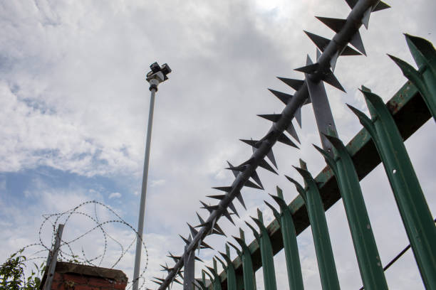 istock Spiked fence and barbed wire with an overcast sky 2155398733