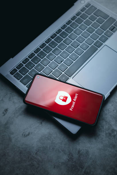istock Smartphone laying on laptop with fraud alert on screen. 2155403759