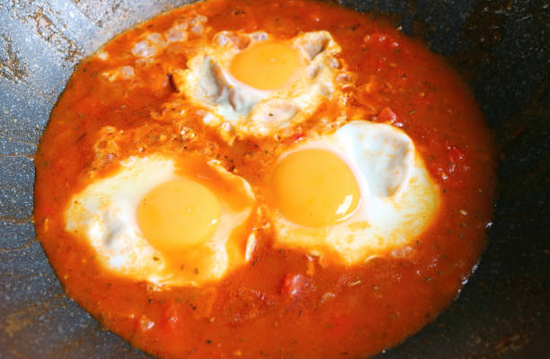 Closeup of eggs being poached in spiced tomato sauce for Shakshuka Dish
