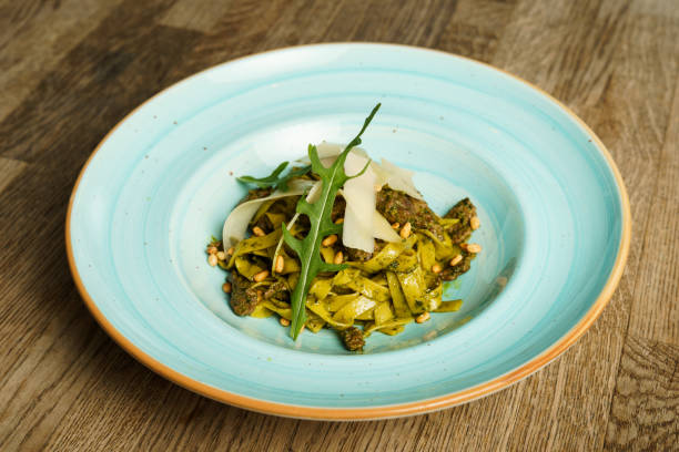 Pasta with pesto sauce and thin slices of cheese