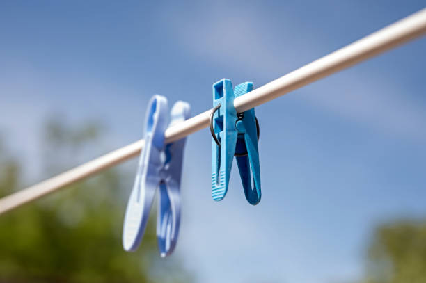 A single wooden clothespin hangs on a wire against a softly blurred background, with ample copy space for designs.