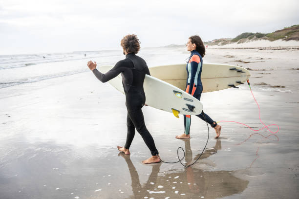 istock Two friends sprint toward the water.Surfing. 2155411603
