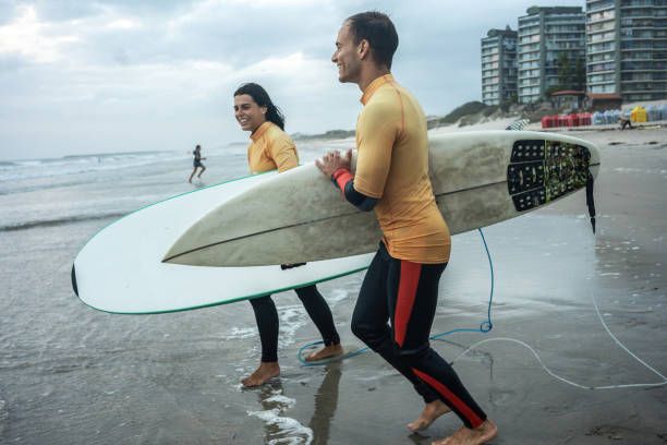 istock Two friends sprint toward the water.Surfing. 2155411734