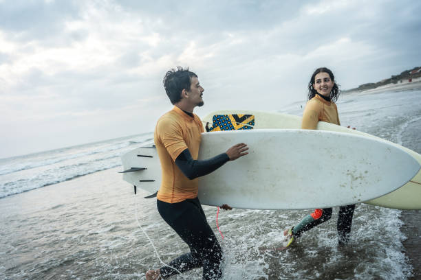 istock Two friends sprint toward the water.Surfing. 2155411749