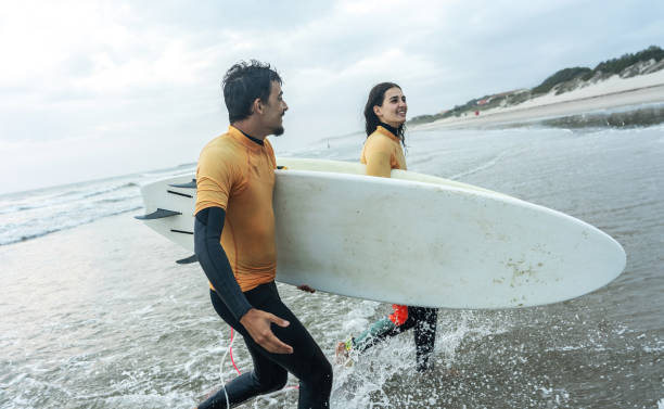 istock Two friends sprint toward the water.Surfing. 2155411759