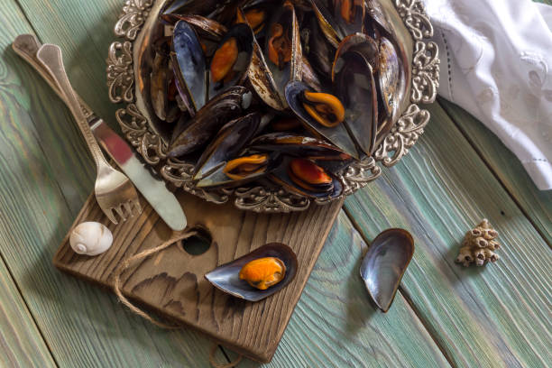 Seafood. The delicious, cooked mussels on a metallic tray close-up on wooden background