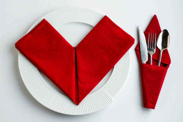 Red paper napkin folded shaped of heart in white plate with elegant cutlery set.Christmas or New Year Concept