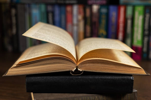 istock opened book, lying on the bookshelf in library 2155414488