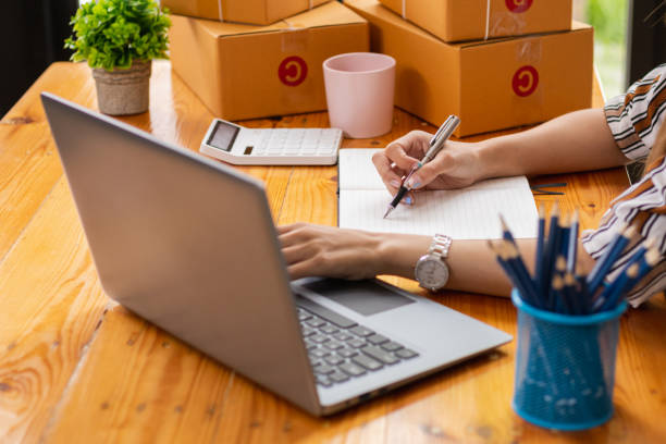 businesswoman decides invest in small SME business at home by using laptop and smartphone do online marketing and sell things online through an application before packing products according to orders. la empresaria decide invertir en pequeñas pymes en casa mediante el uso de computadoras portátiles y teléfonos inteligentes, hacer marketing en línea y vender cosas en línea a través de una aplicación antes de empacar productos de acuerdo con los pe