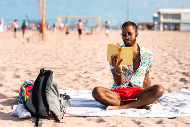 istock African boy reading a book on the beach in the sand 2155417143