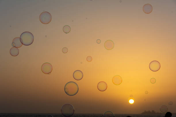 Many colorful soap bubbles float in the orange sky at sunset