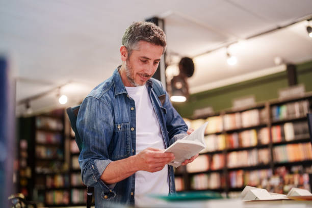 istock Man examining the books in bookstore shelves. 2155422502