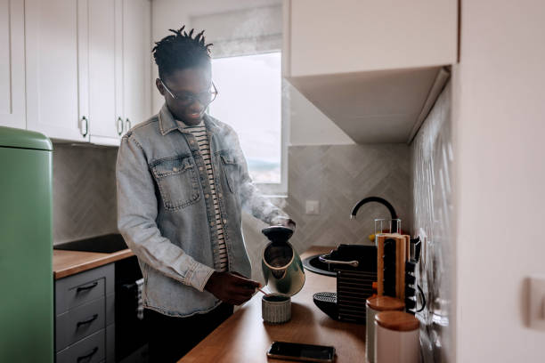 istock Young causally clothed man making coffee in a domestic kitchen at home 2155422648