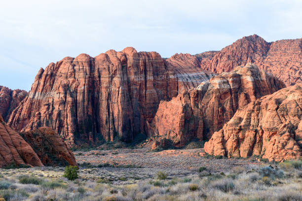 The towering red Navajo sandstone cliffs at Snow Canyon State Park. The breathtaking rock formations rise steeply from the grassy valley below. Taken in the early morning light - St George, Utah, USA